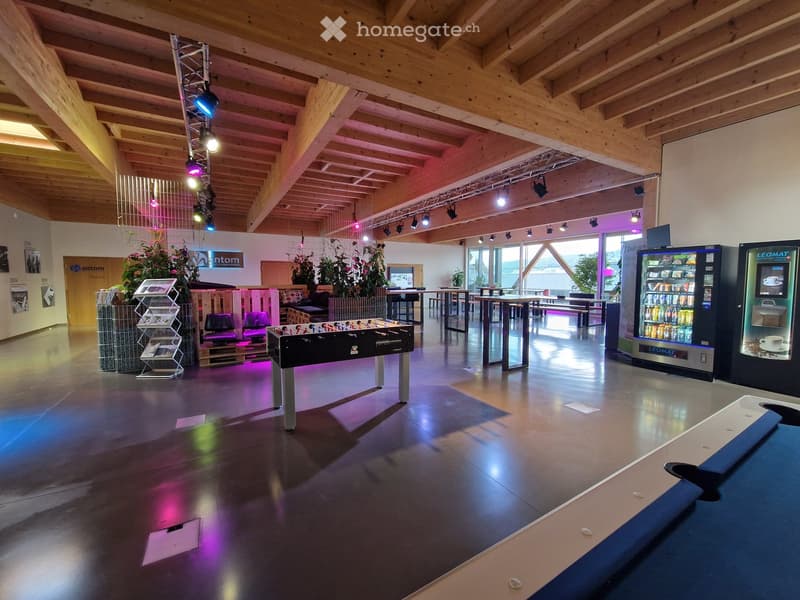 large room, open area, wooden ceiling, gaming table, tables, chairs, potted plants, vending machines, stage area with spotlights