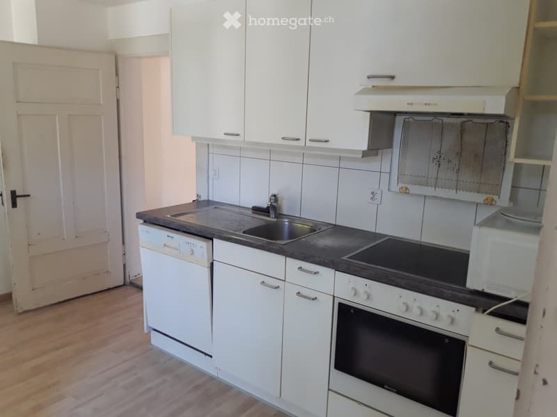 white cabinets, wooden floor, white sink, dishwasher, gas oven, tile wall, countertop
