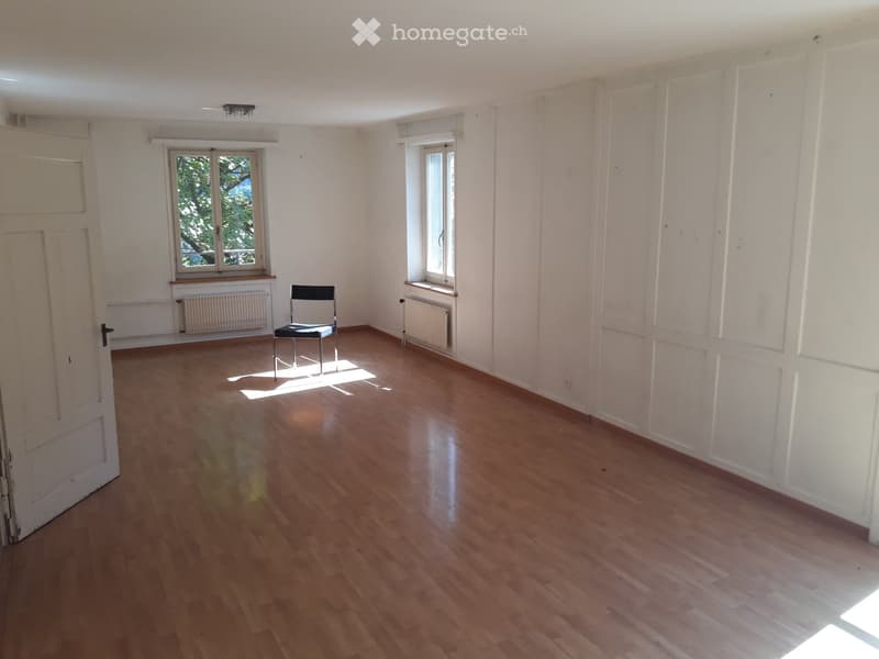 empty room with wooden floor, white walls, 2 windows, chair, heaters, door