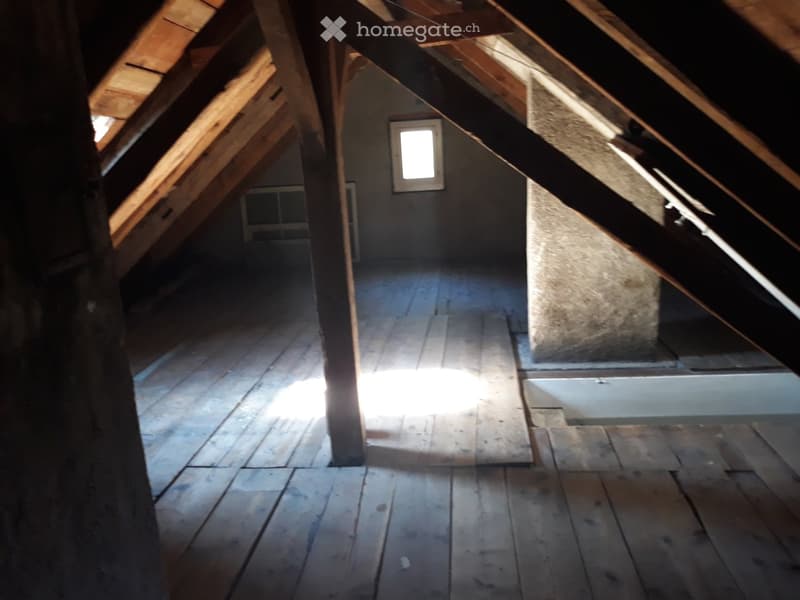 Attic room with wooden beams, wooden floor, small window, unfurnished