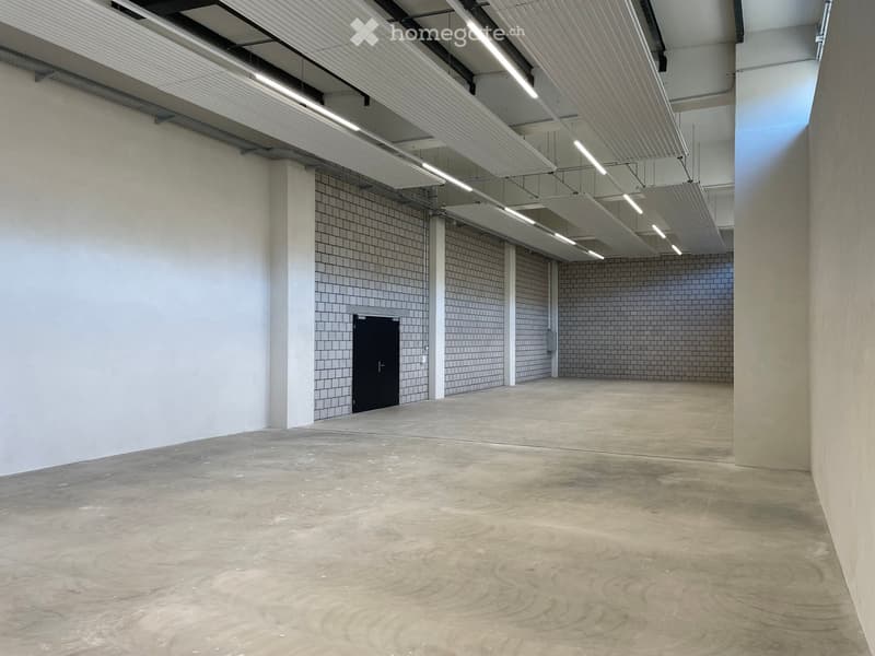 Open space, white walls, exposed ceiling beams, a single door at the end