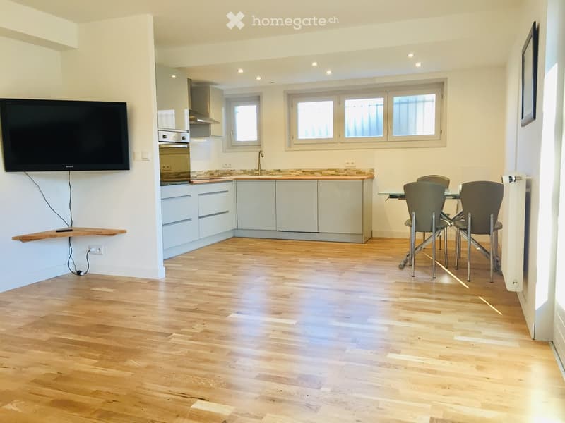 wooden floor, white walls, modern appliances, dining table and chairs, flat screen TV, cabinets, and windows