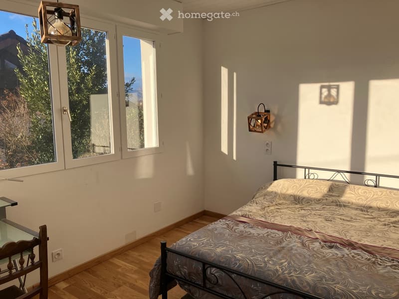 single bed, large window with double glass panes, lamp on wall, desk and chair