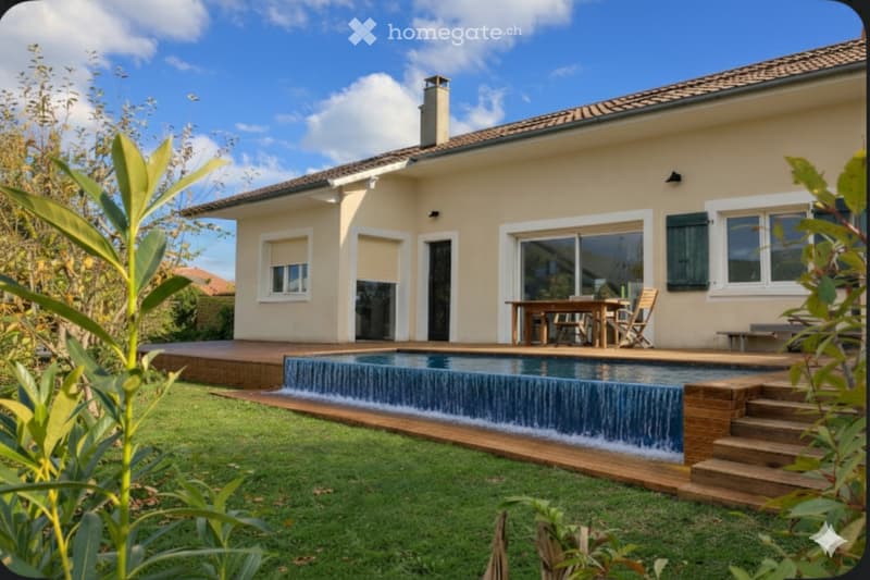 A two-story house with beige exterior, glass windows, a large outdoor wooden deck with stairs, a wooden dining table, and a swimming pool.