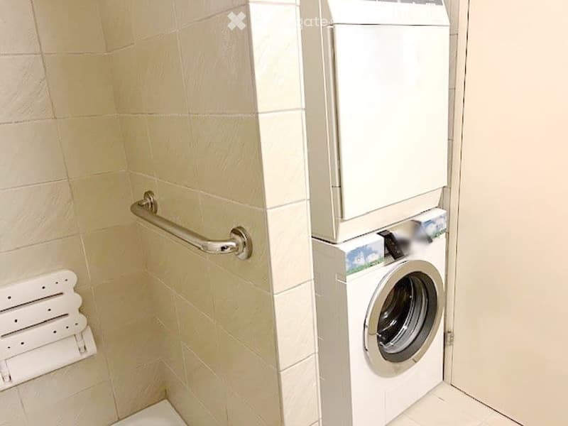Small room with washing machine and shower chair