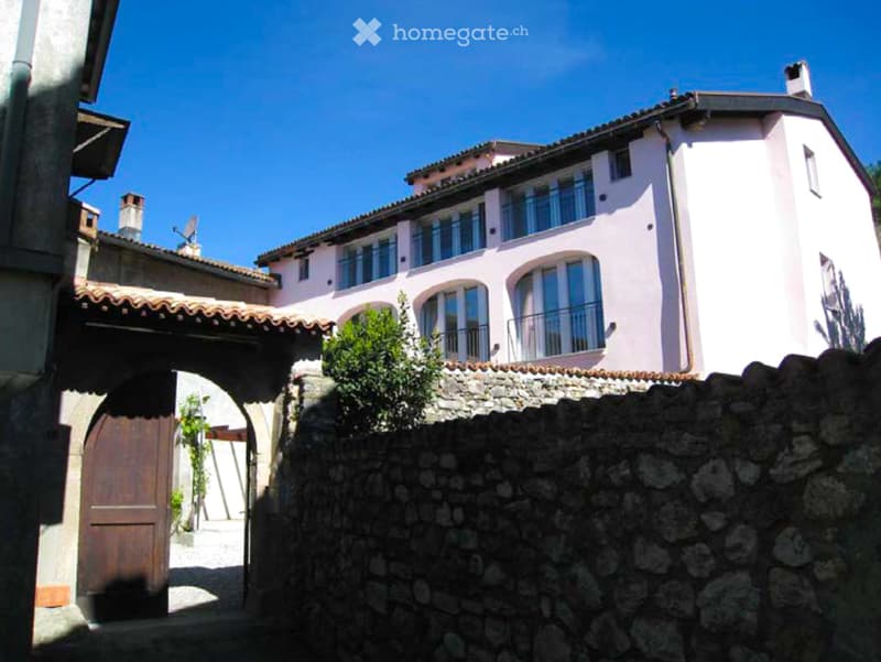 pink exterior, wooden archway, stone wall, large windows, balconies