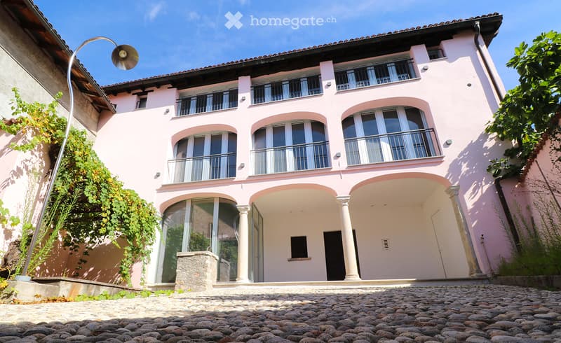 3 story house, pink exterior, glass windows, several balconies, courtyard