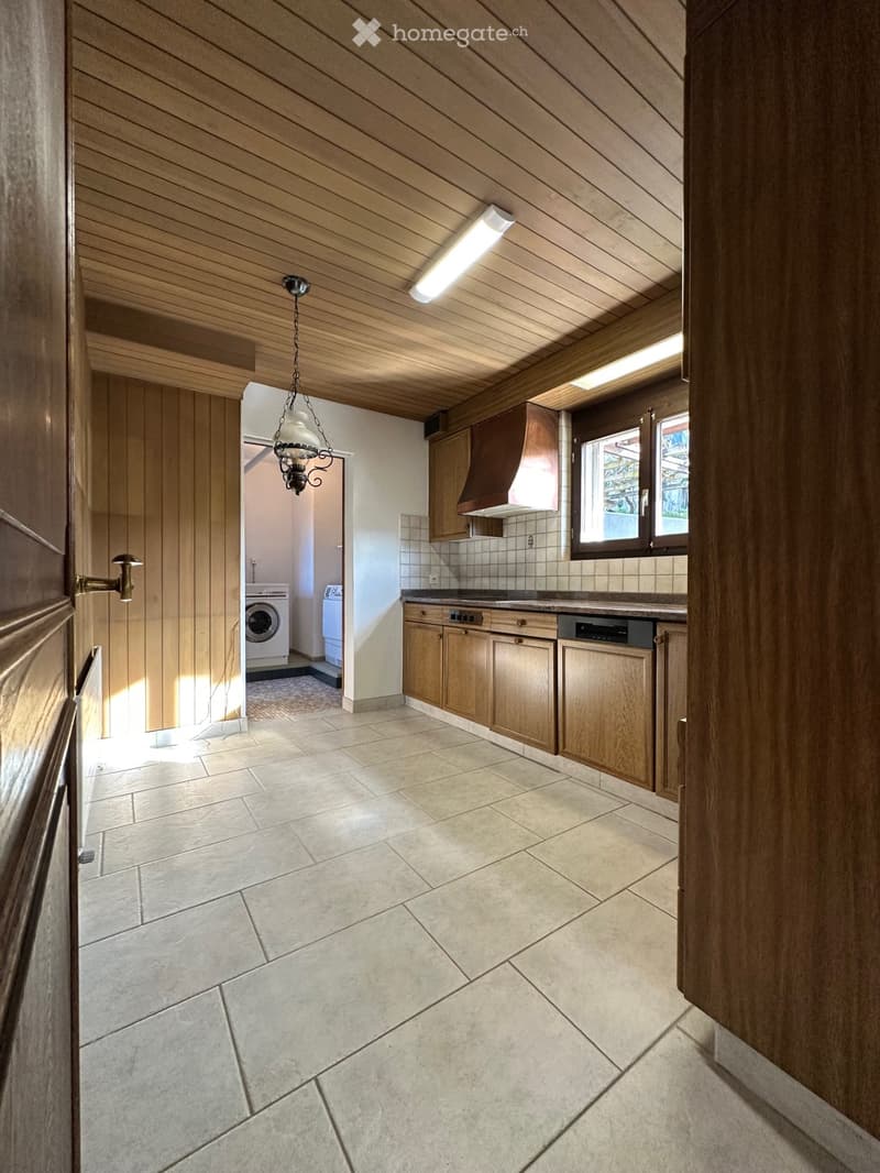 kitchen area with tiled floor, wooden cabinets, white tiled walls, white washing machine, dishwasher, large window, chandelier
