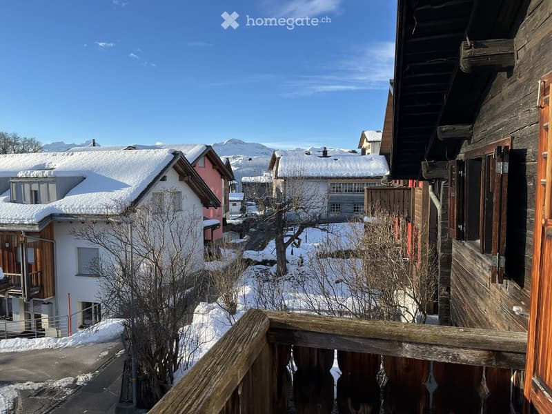 wooden buildings with snow on the roofs, snow-covered ground, balcony with wooden railing