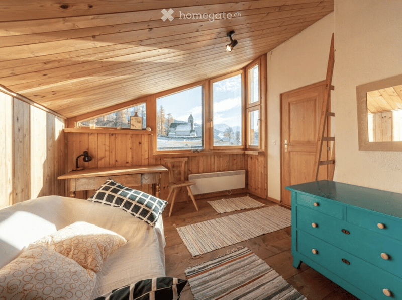 bedroom with wooden ceiling, desk with lamp, sofa, chest of drawers, carpets, large windows, wooden door, mirror on the wall