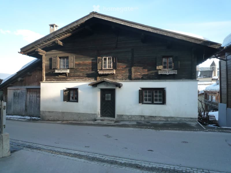 Wooden exterior, white lower floor, three windows on each floor, black door, single storey