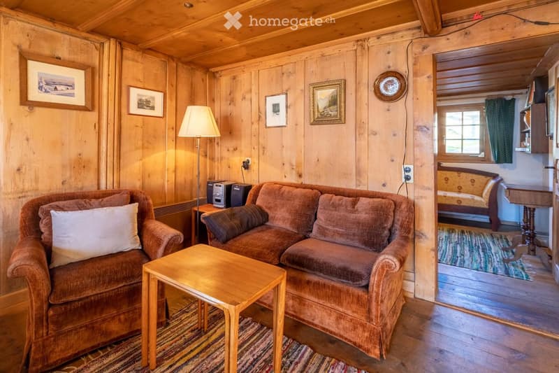 Two couches, wooden table, wooden lamp, wooden floor, wooden wall