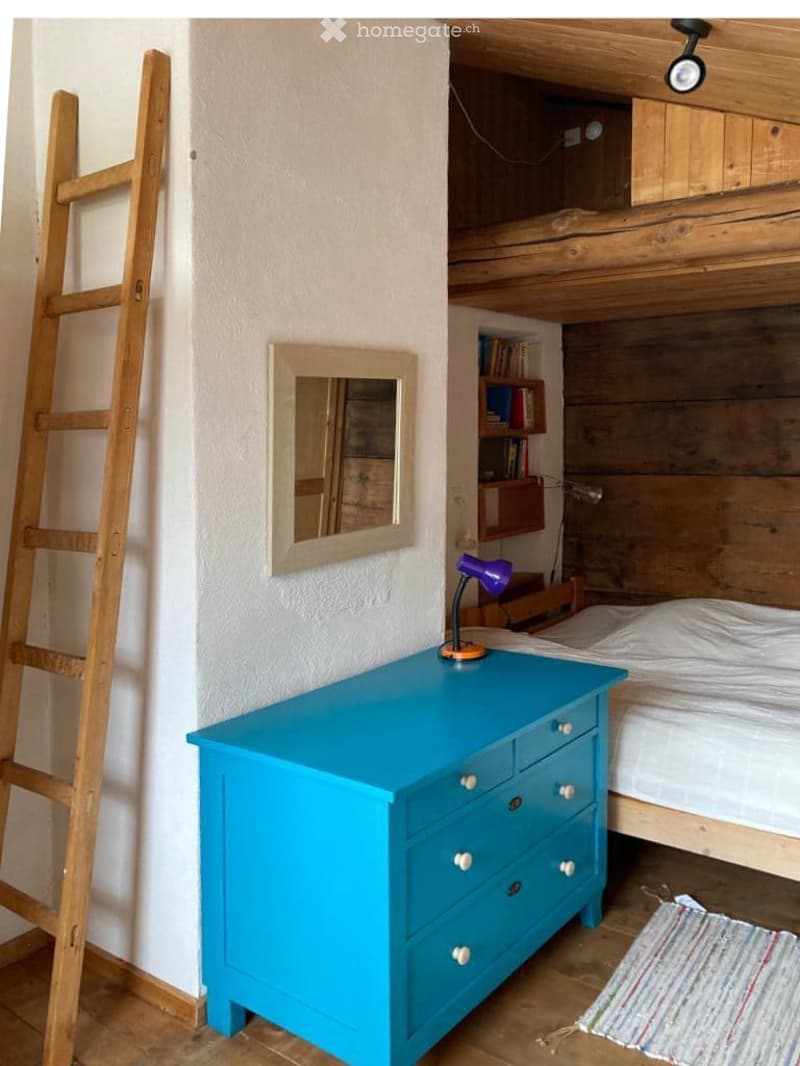 wooden bed, blue dresser, mirror, wooden ladder, books on shelves