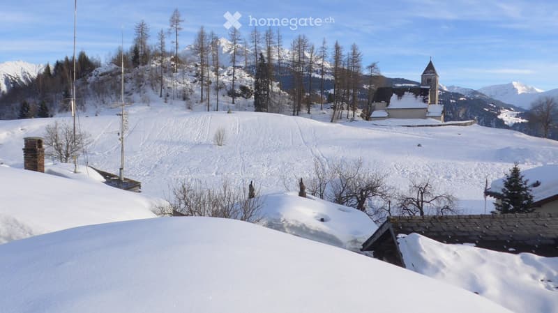 snowy landscape with a church, a small village, and mountains in the background