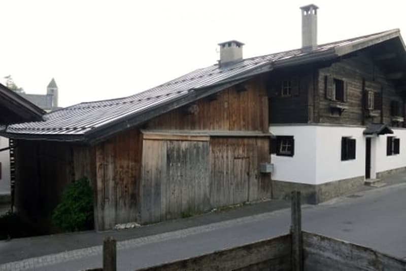 Two-story wooden house with chimneys, metal roof, garage door
