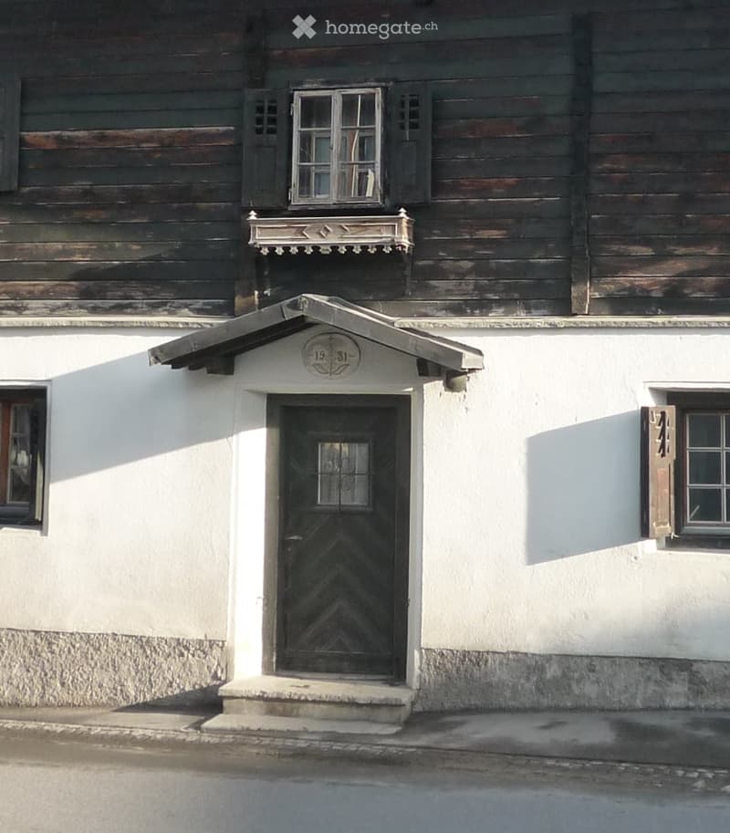Traditional wooden house, 2 stories, wooden walls, windows with shutters, white walls, central wooden door, number plate above the door, ground floor steps