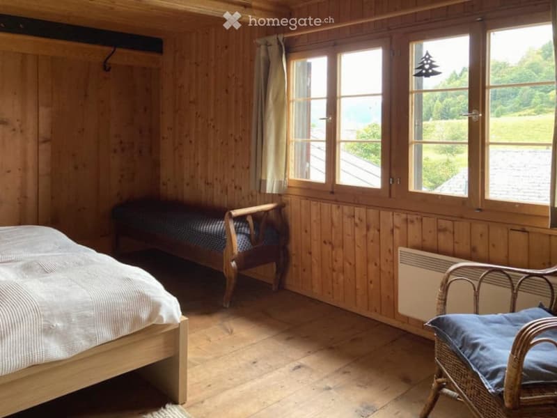 Bedroom with bed, bench, and large windows with a scenic view.
