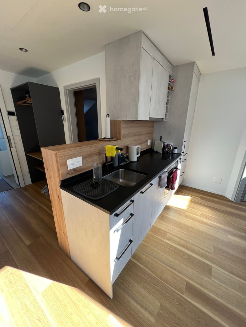 wooden countertop, black marble top, silver sink, wooden flooring, cabinets, light fixtures