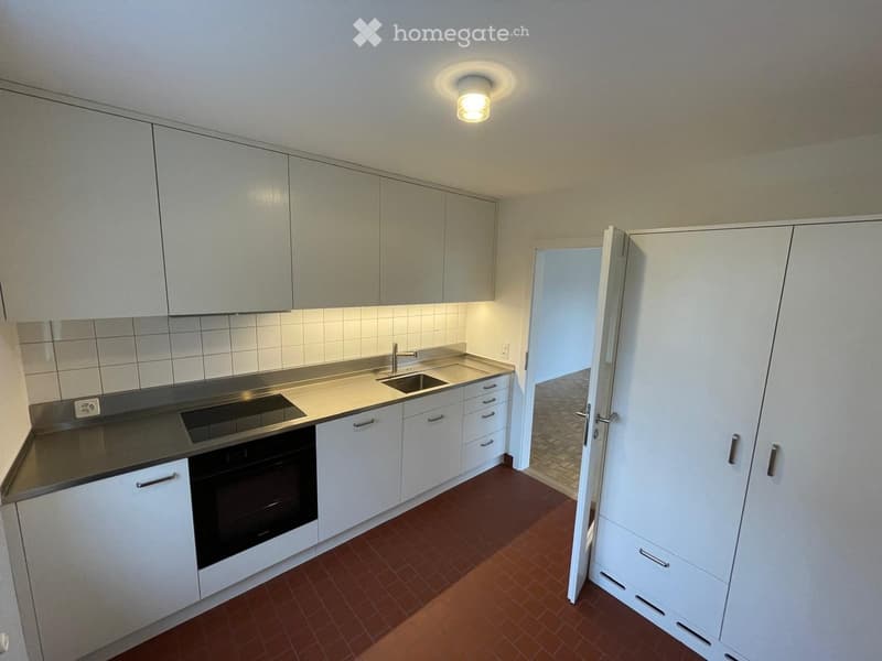 modern minimalist kitchen, white cabinets, stainless steel counter, white tiled backsplash, tiled flooring, built-in oven and dishwasher, large sink with faucet, recessed lighting, and additional storage cabinets