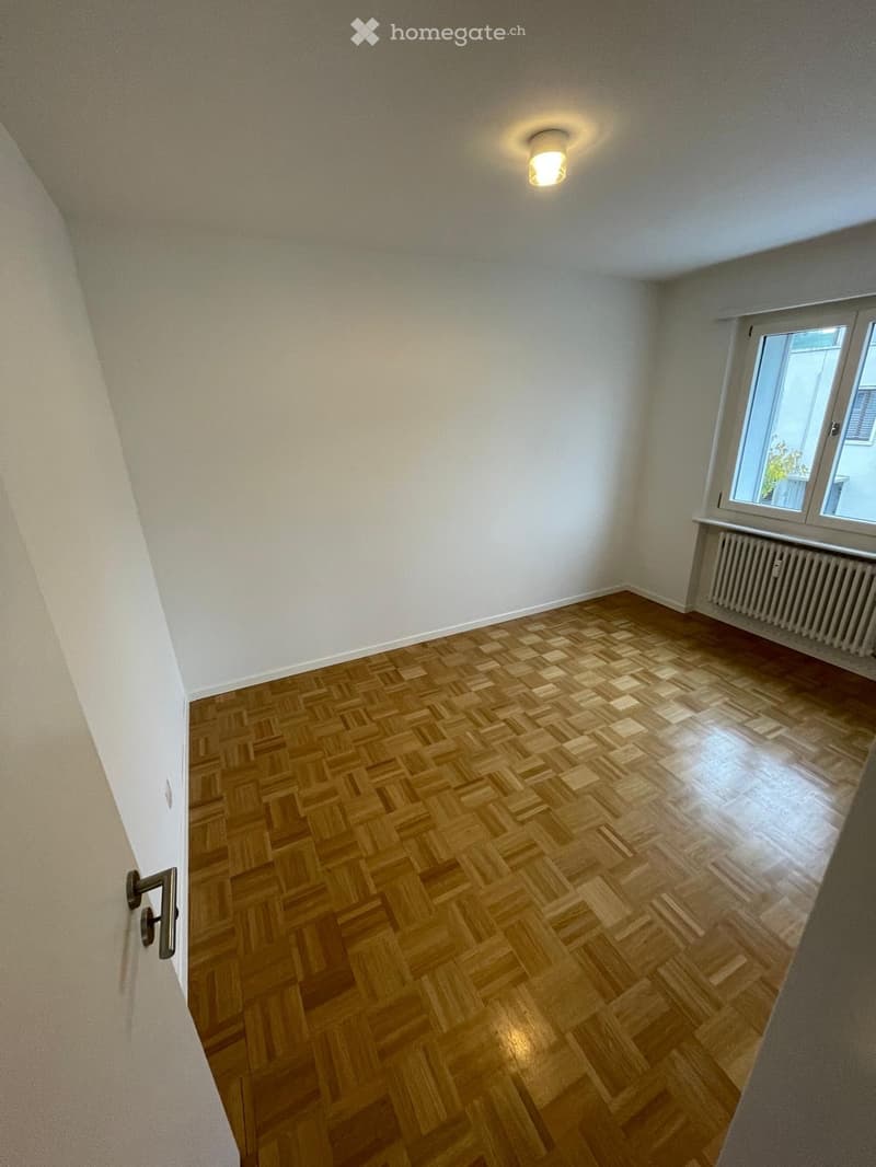 empty room, wooden floor, white walls, radiator, window, ceiling light