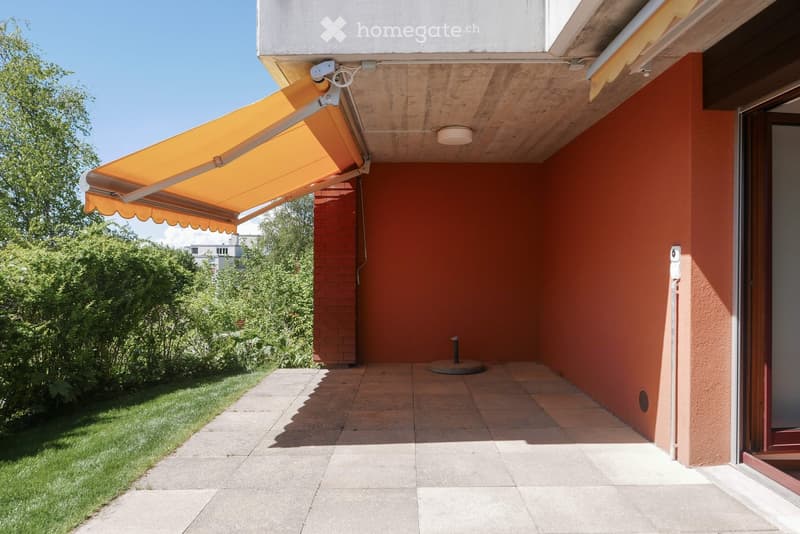 Balcony with orange awning, tiled floor, and a small round table stand.