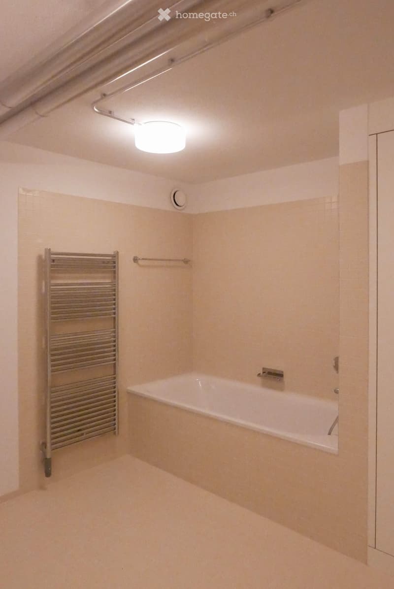 Modern bathroom with a bathtub, radiator, and tiled walls and floor.