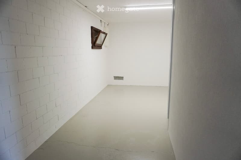 empty room with concrete floor, white brick walls, a ceiling light, and a small window