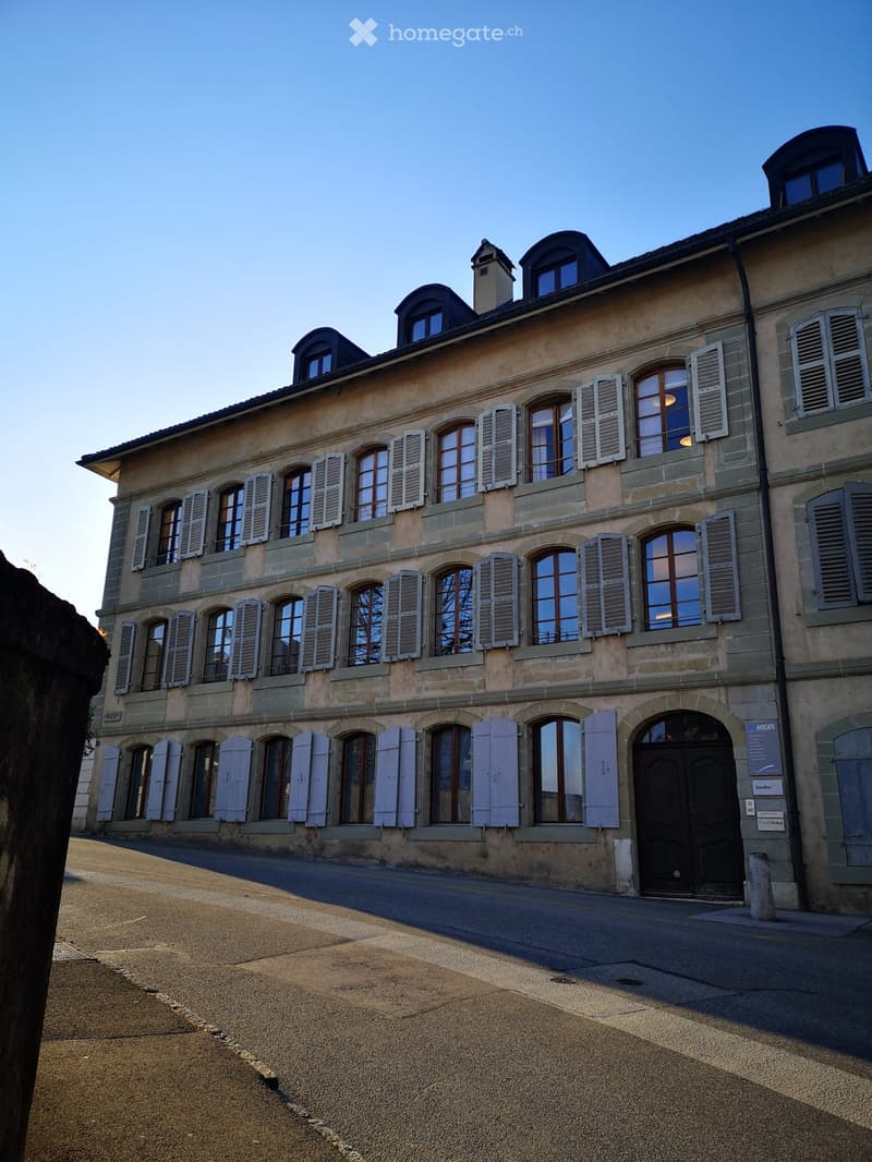 Old building with multiple windows and closed doors, beige exterior, no visible indoor or outdoor amenities
