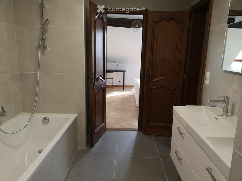 bathroom with bathtub, modern shower, double sink, wooden floors, wooden doors, mirrored cabinet, lamp