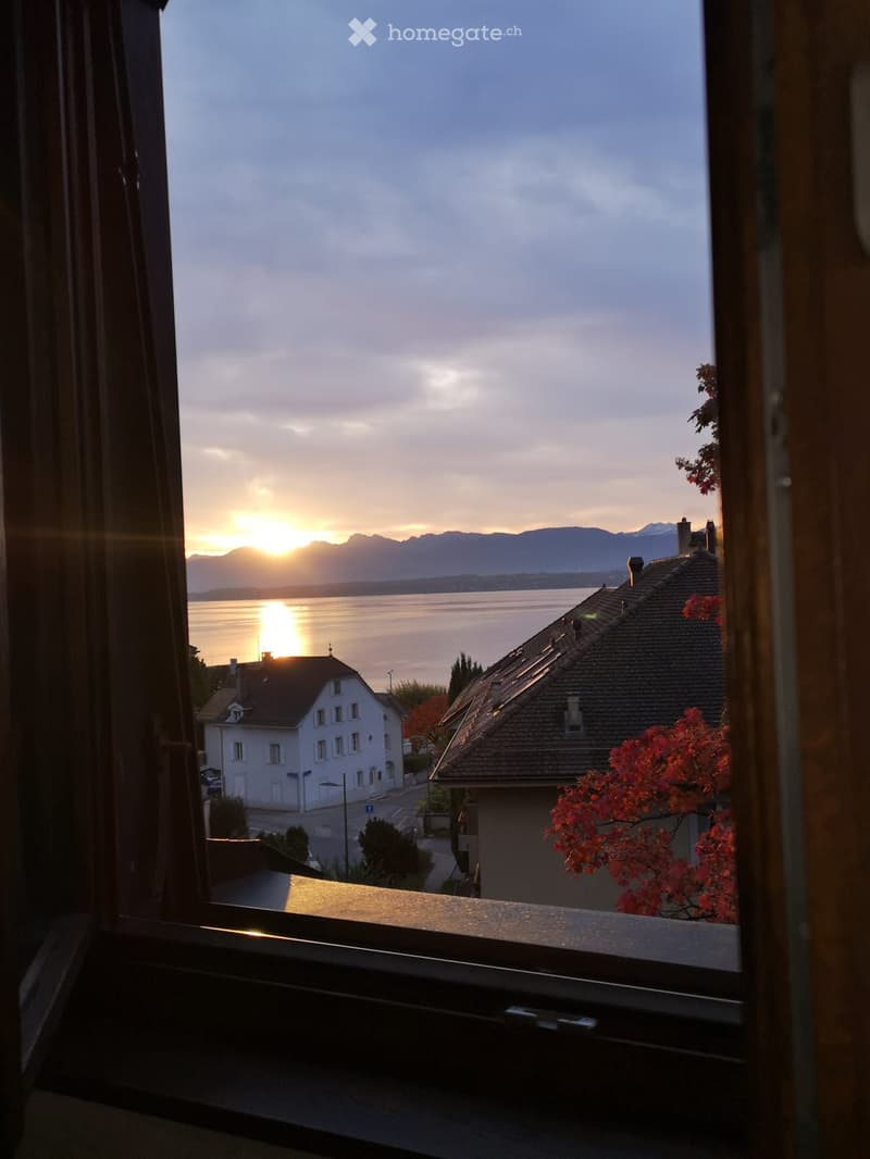 Sunset view from window, mountains and water in the distance, residential buildings visible