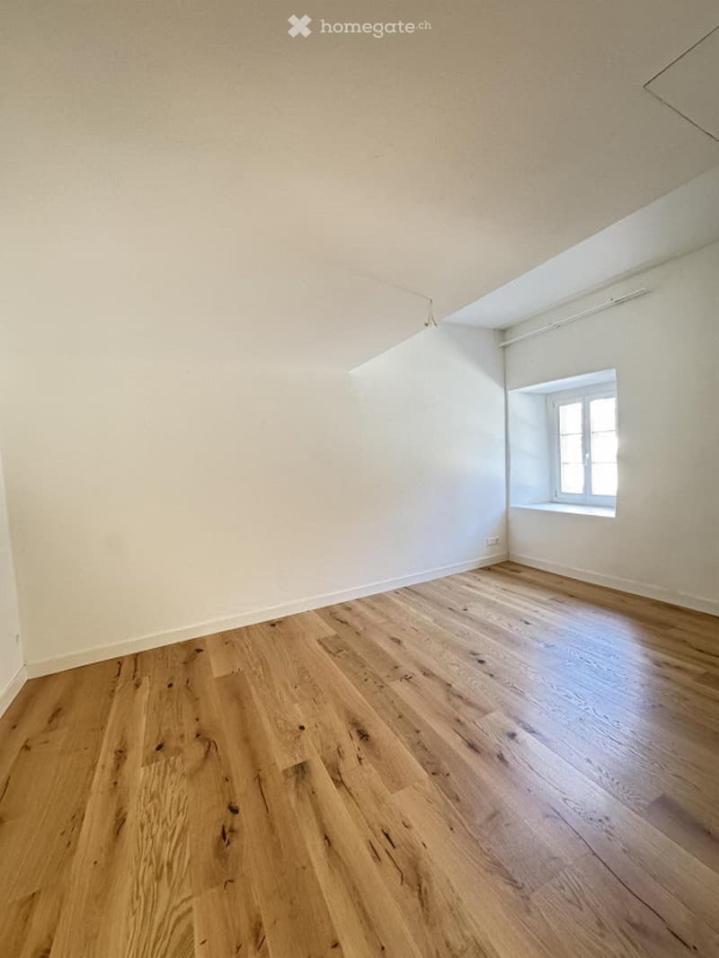 Empty room, hardwood floor, white walls, window.