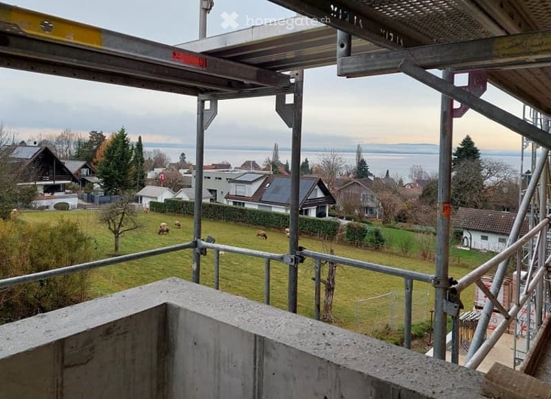 view from balcony, grass field, houses, sea in background