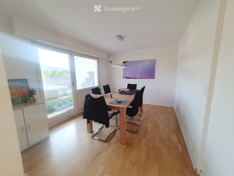 Dining room with dining table, chairs, and glass door leading to a balcony with plants