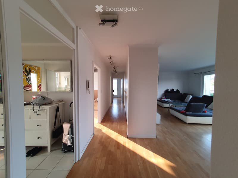 long hallway with wooden floors and white walls, hallway light, mirror and drawers in entrance