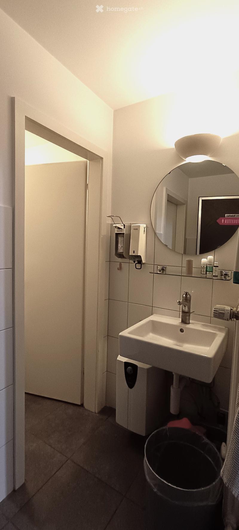 bathroom with white tile, white sink, white mirror, hand dryer, door