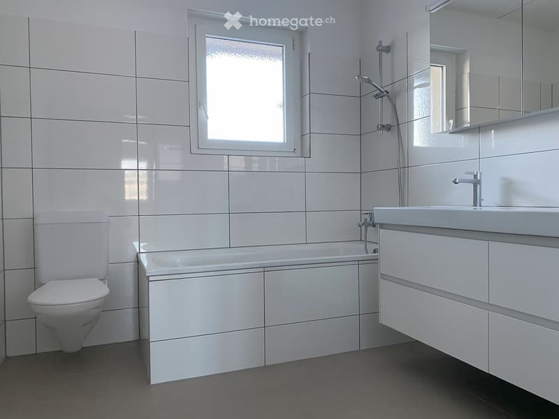modern bathroom with white tiles, toilet, bathtub, sink, mirror, and shower