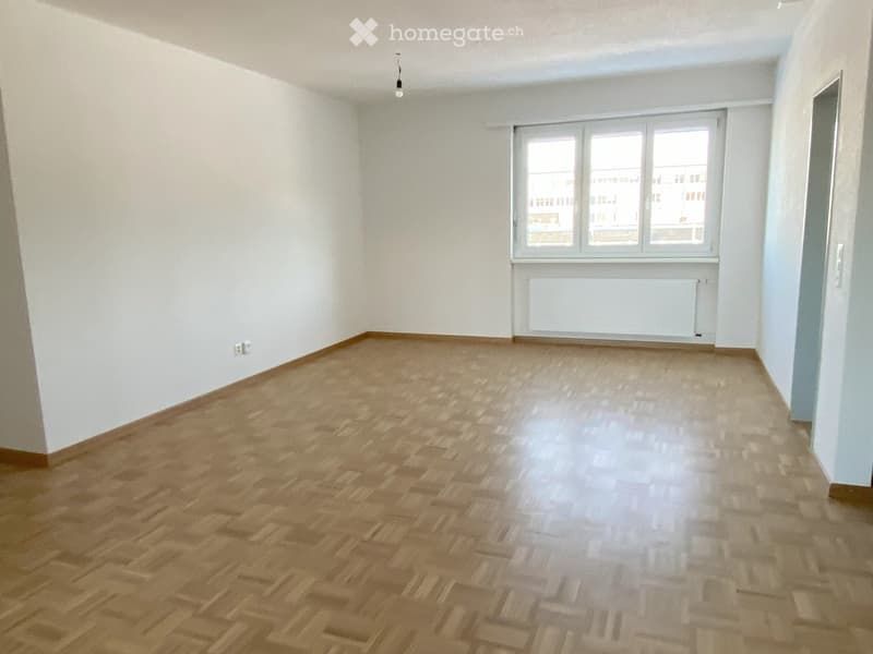 spacious room, white walls, wooden floor, large window, radiator