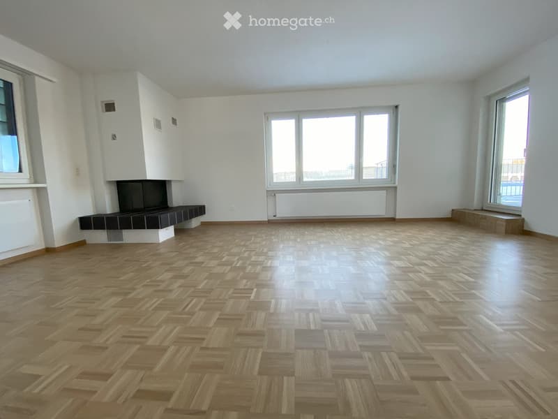 large open room, wooden parquet flooring, large windows, fireplace, bench