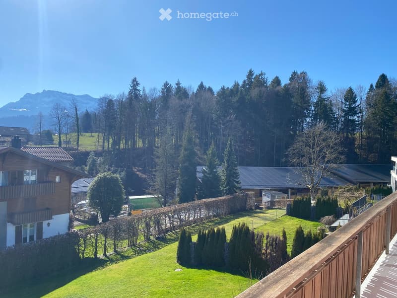 Balcony with a view of a well-manicured lawn and a forested area in the background