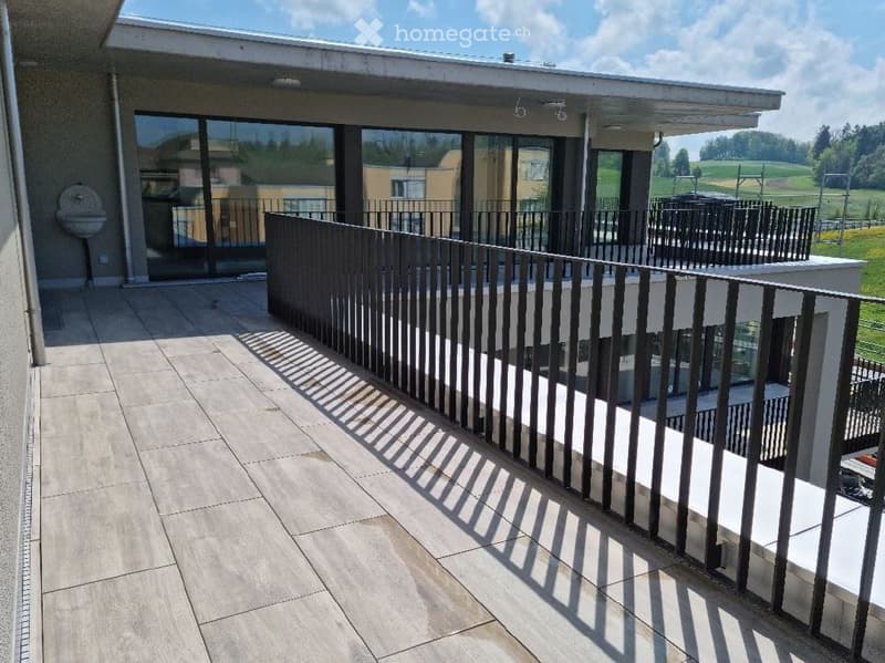 Terraced balcony with black railings, tiled flooring, and a view of a grassy field