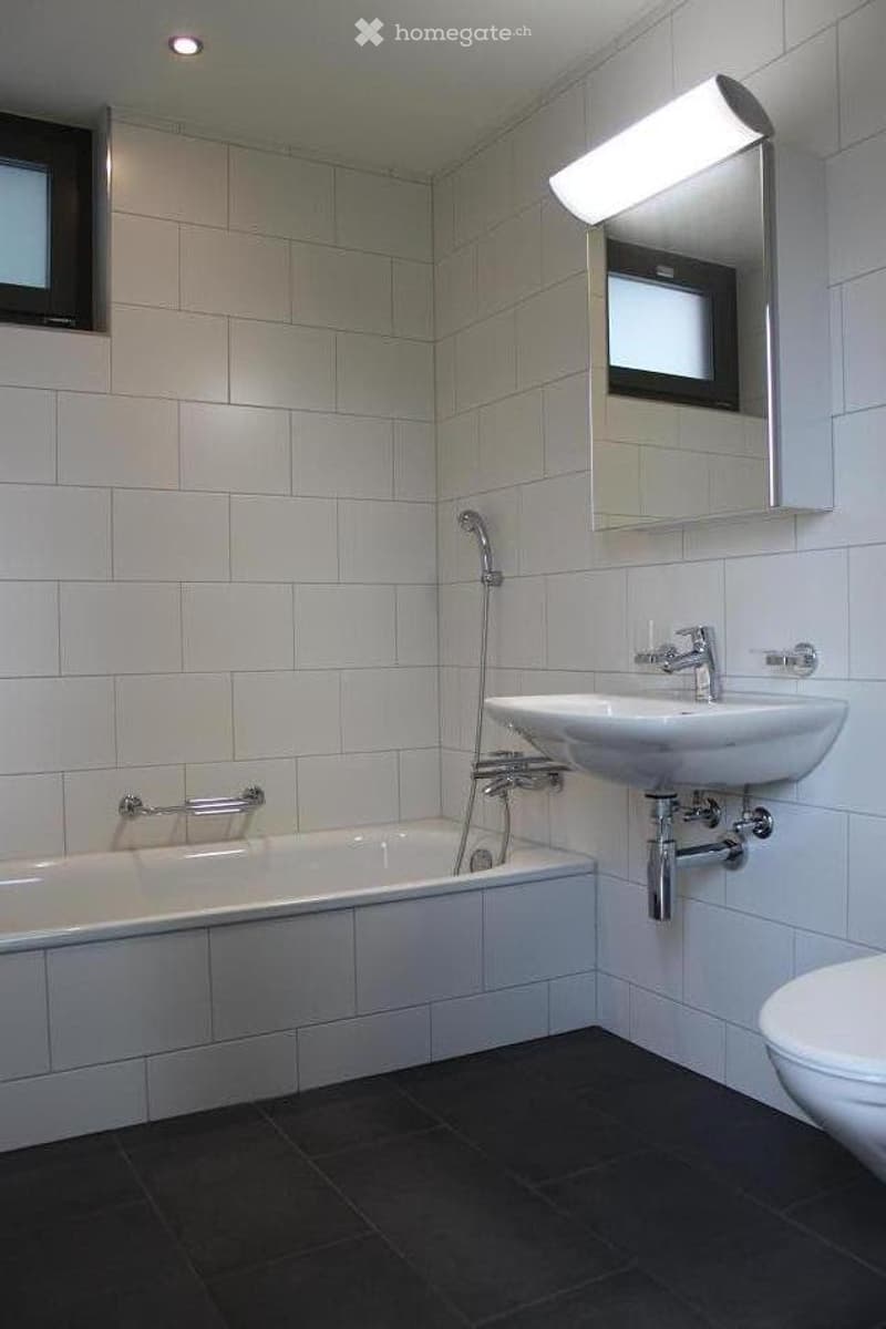 tiled walls, tiled floor, bathtub, toilet, sink, mirror, showerhead, towel racks