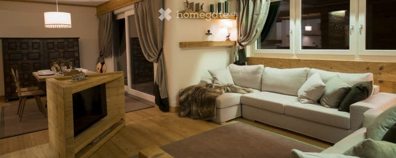 L-shaped sofa, white couch, two wooden tables, dining table, curtained windows, carpet, wooden floor, lamp, television