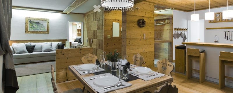dining table, chairs, 4 plates, silverware, wine glasses, wooden flooring, wood paneling, lamp, dining counter, sofa, rug, picture frame