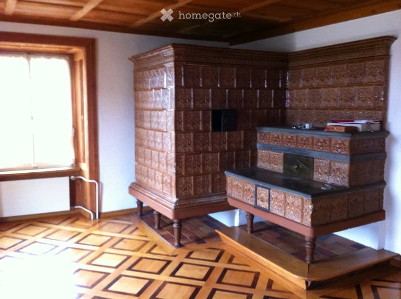 Fireplace, decorative tilework, wooden floor, window with white curtain