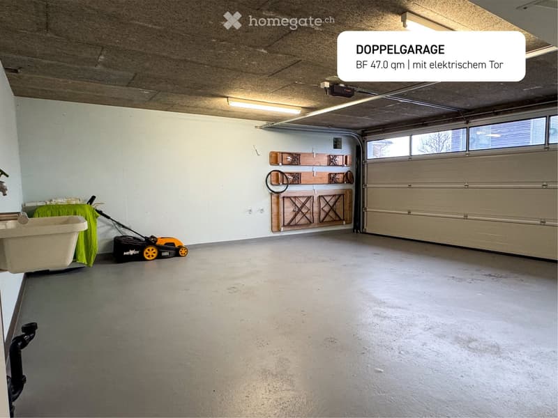Spacious double garage with electrical doors, a sink, hooks for storage, and two vehicle lights