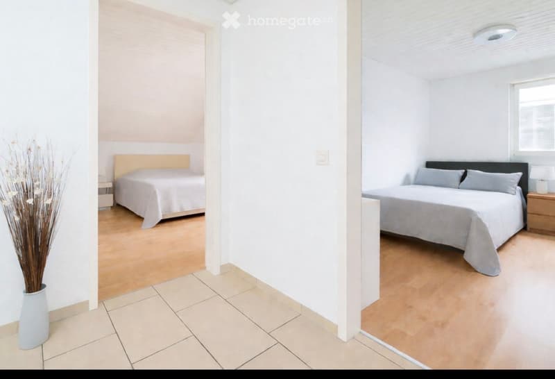 spacious bedroom with hardwood floors and large beds, one with wooden headboard, small room with window, minimalist decor, vase with dry plants