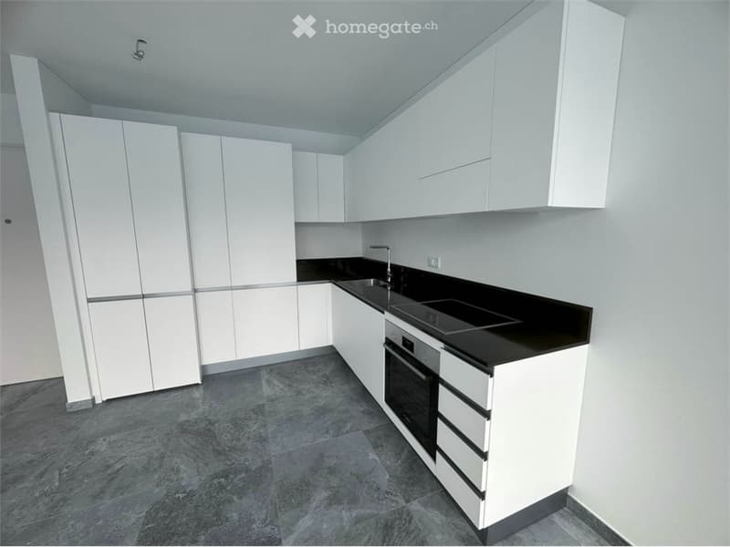 Modern kitchen with white cabinets, black countertops, grey tiled floor, built-in oven and sink