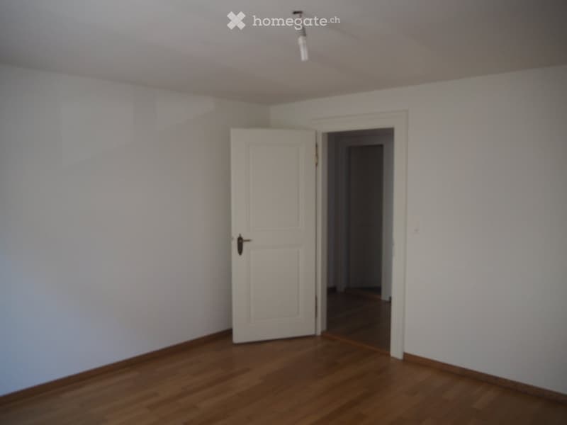 empty room, wooden floor, white walls, open door leading to another room, no furniture