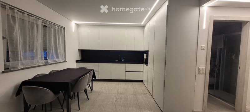 Dining area with a dining table and chairs, a kitchen area with an island and cabinets