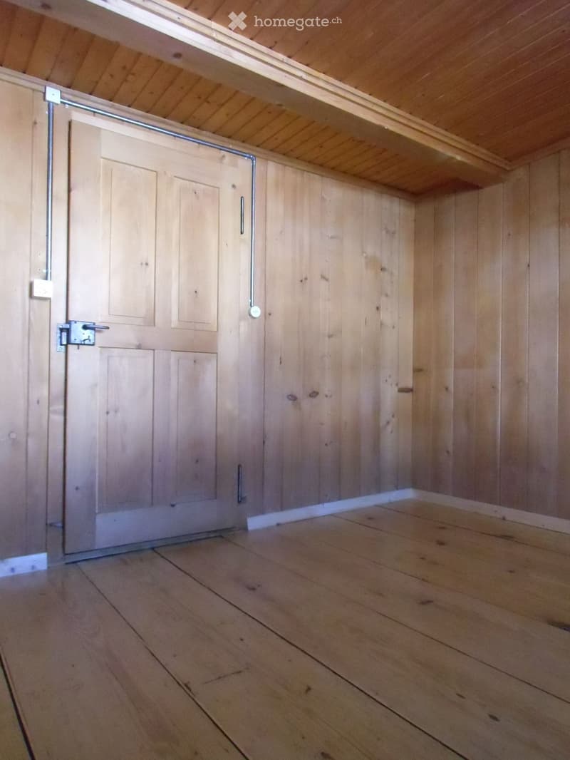 Empty room with wooden flooring and wooden walls.